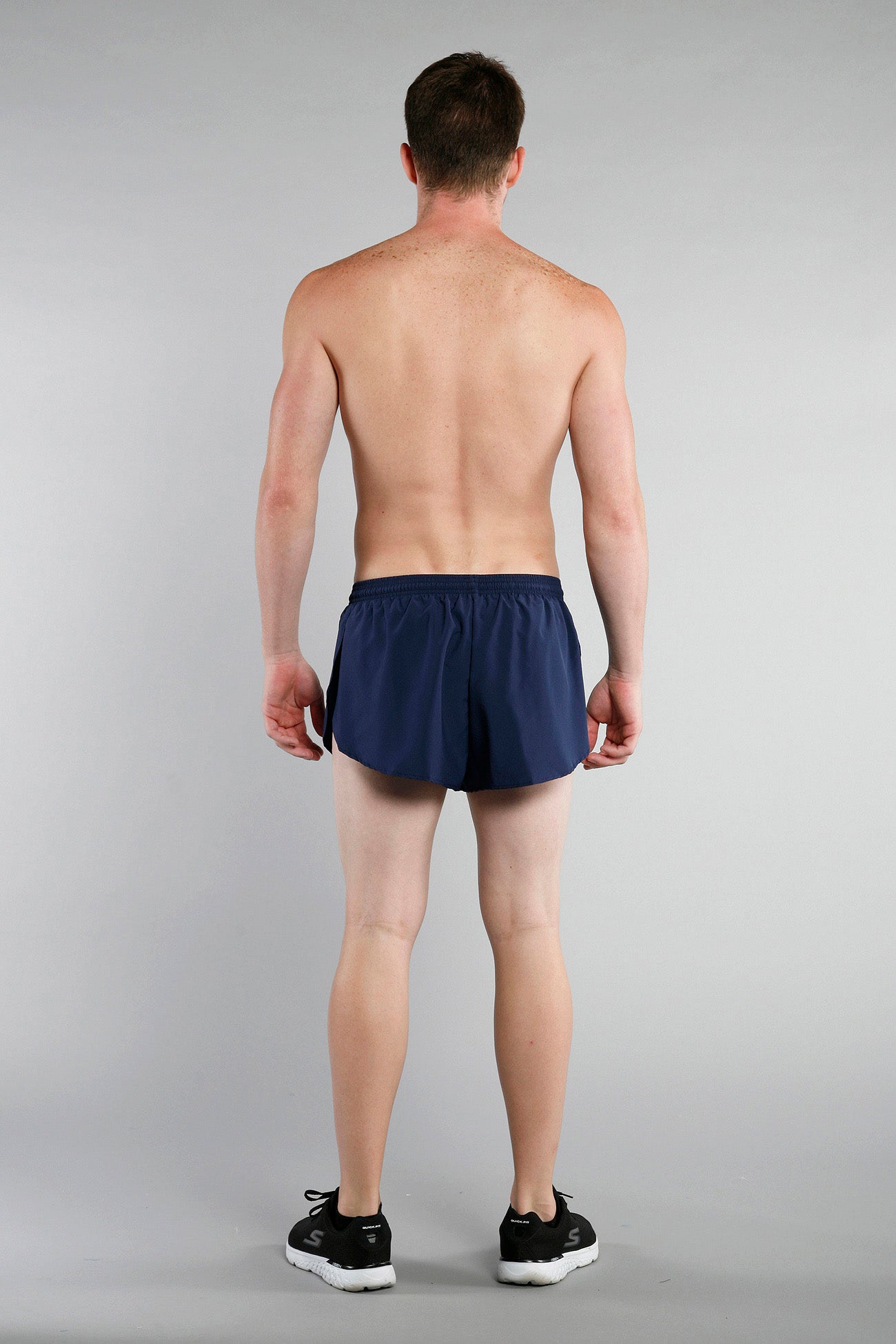 Men's Flag 1" Elite Split Shorts in navy blue shown from the back on a male model wearing black Skechers sneakers, displaying the lightweight split-hem design and elastic waistband.