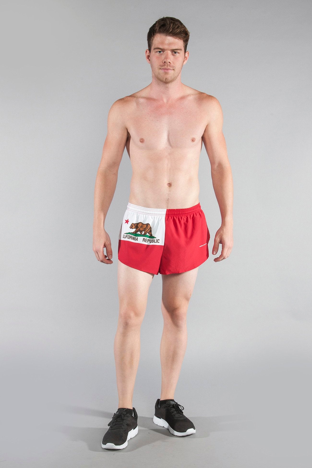 Men's Flag 1" Elite Split Shorts in California Republic bear flag design featuring red and white panels with a grizzly bear graphic, modeled by a shirtless man wearing black sneakers.