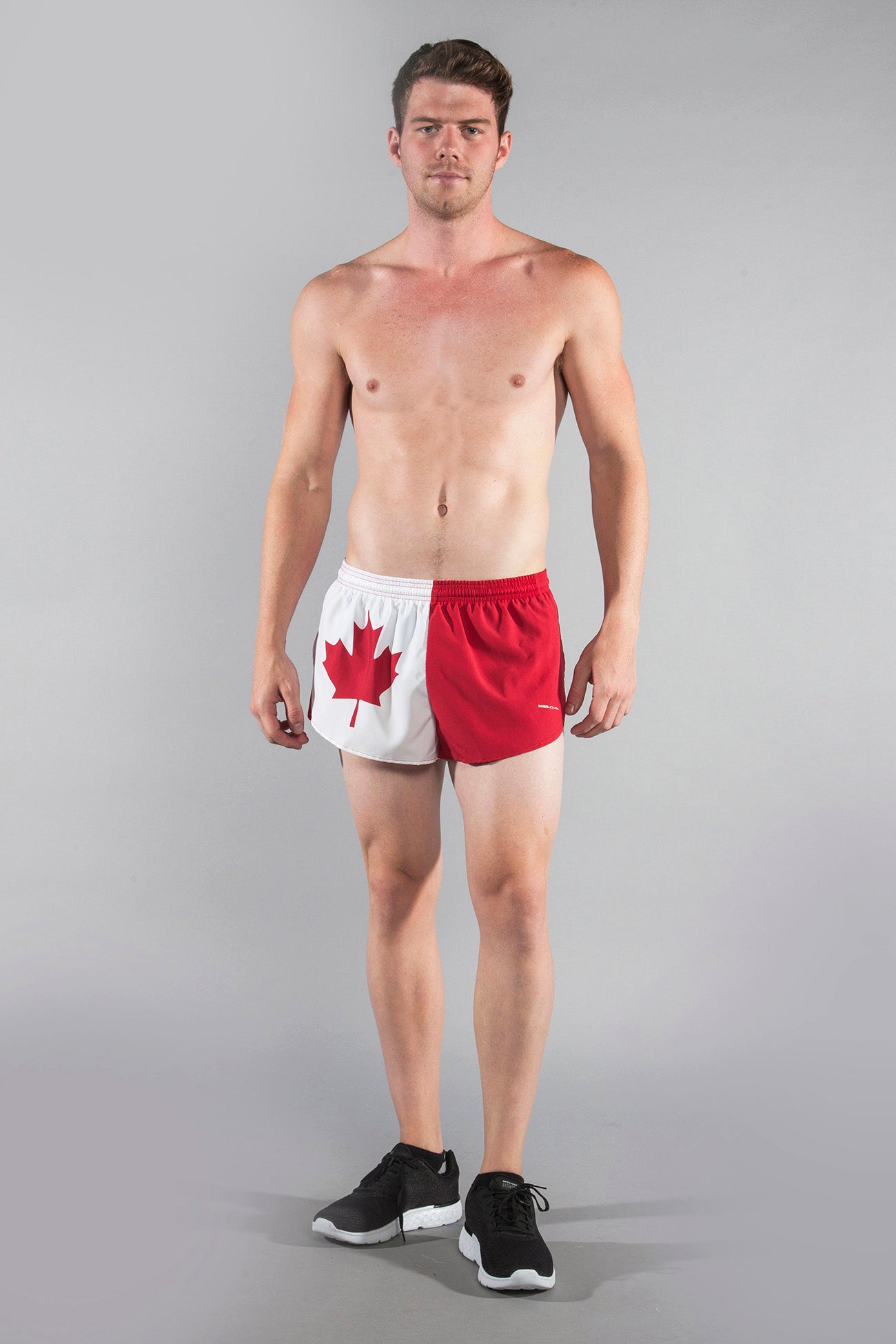 Men's Flag 1" Elite Split Shorts in Canada design, featuring red and white panels with a bold red maple leaf, modeled by a shirtless male athlete paired with black sneakers.