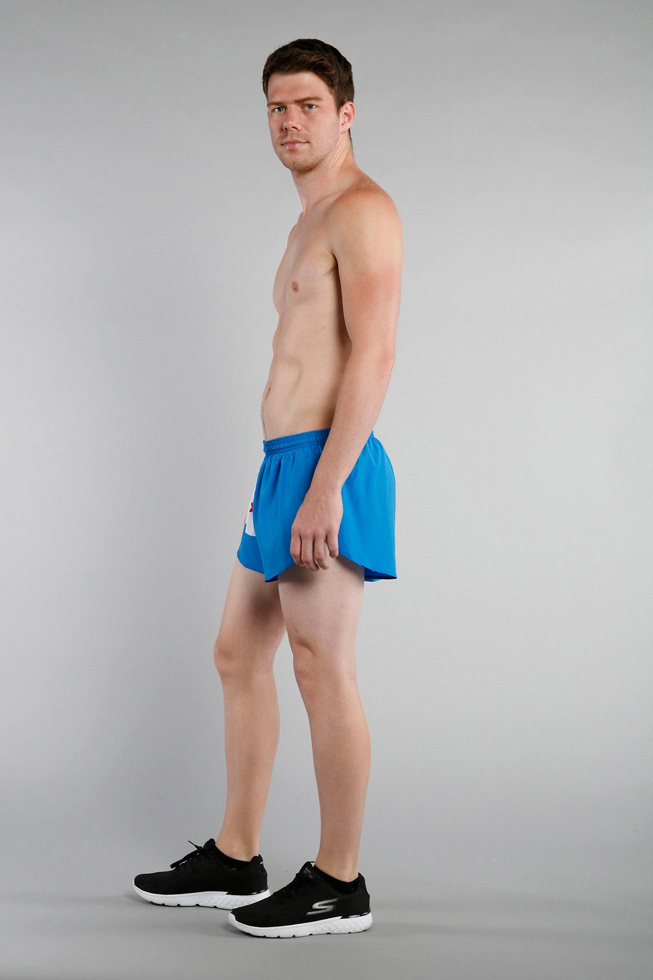 Men's Flag 1" Elite Split Shorts in bright blue with a white and red Chicago flag graphic, modeled shirtless with black Skechers sneakers against a gray background.