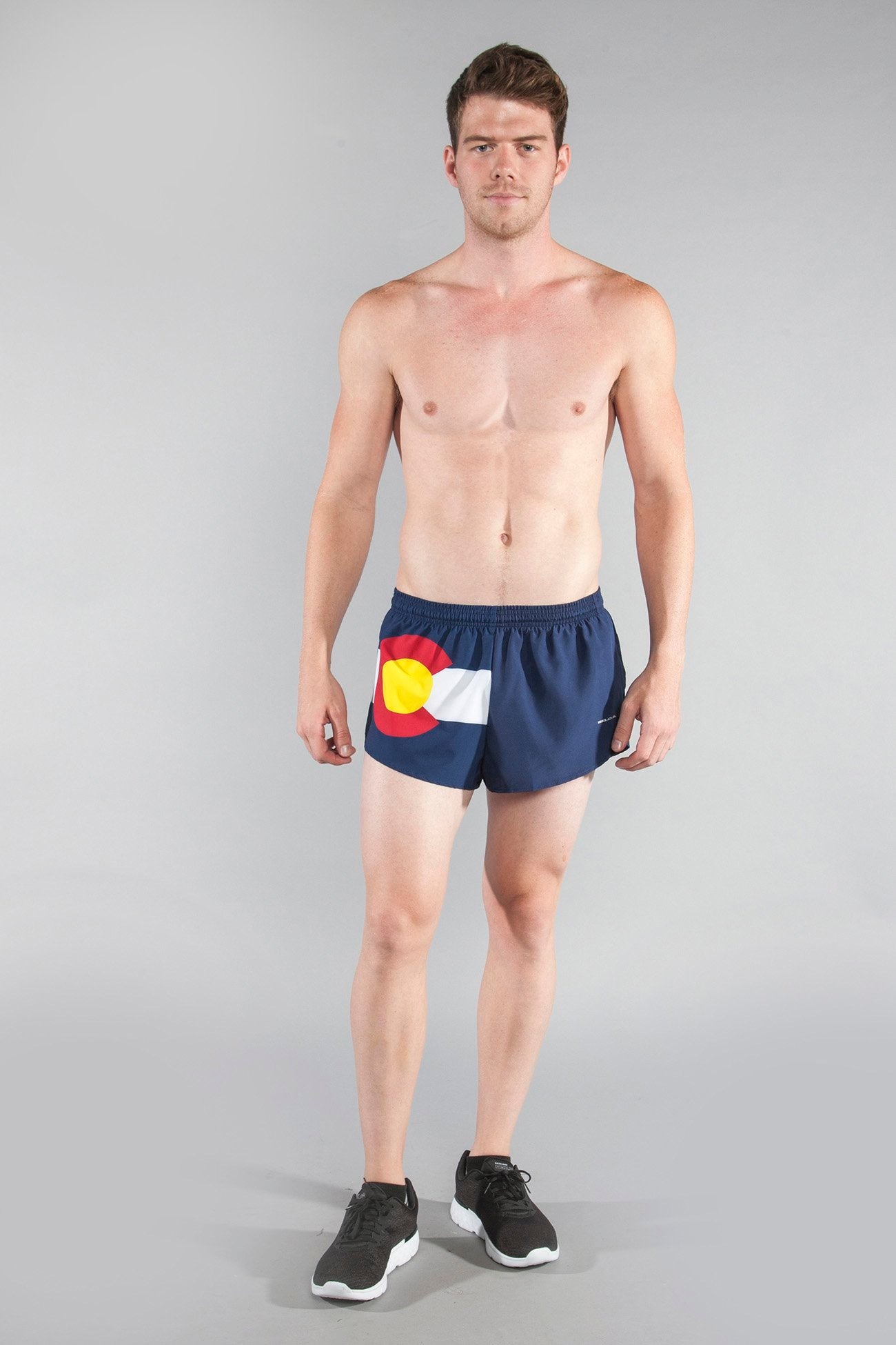 Men's Flag 1" Elite Split Shorts in Colorado design, featuring a navy blue fabric with the Colorado state flag graphic including red, yellow, and white details, modeled by a shirtless man wearing black sneakers.