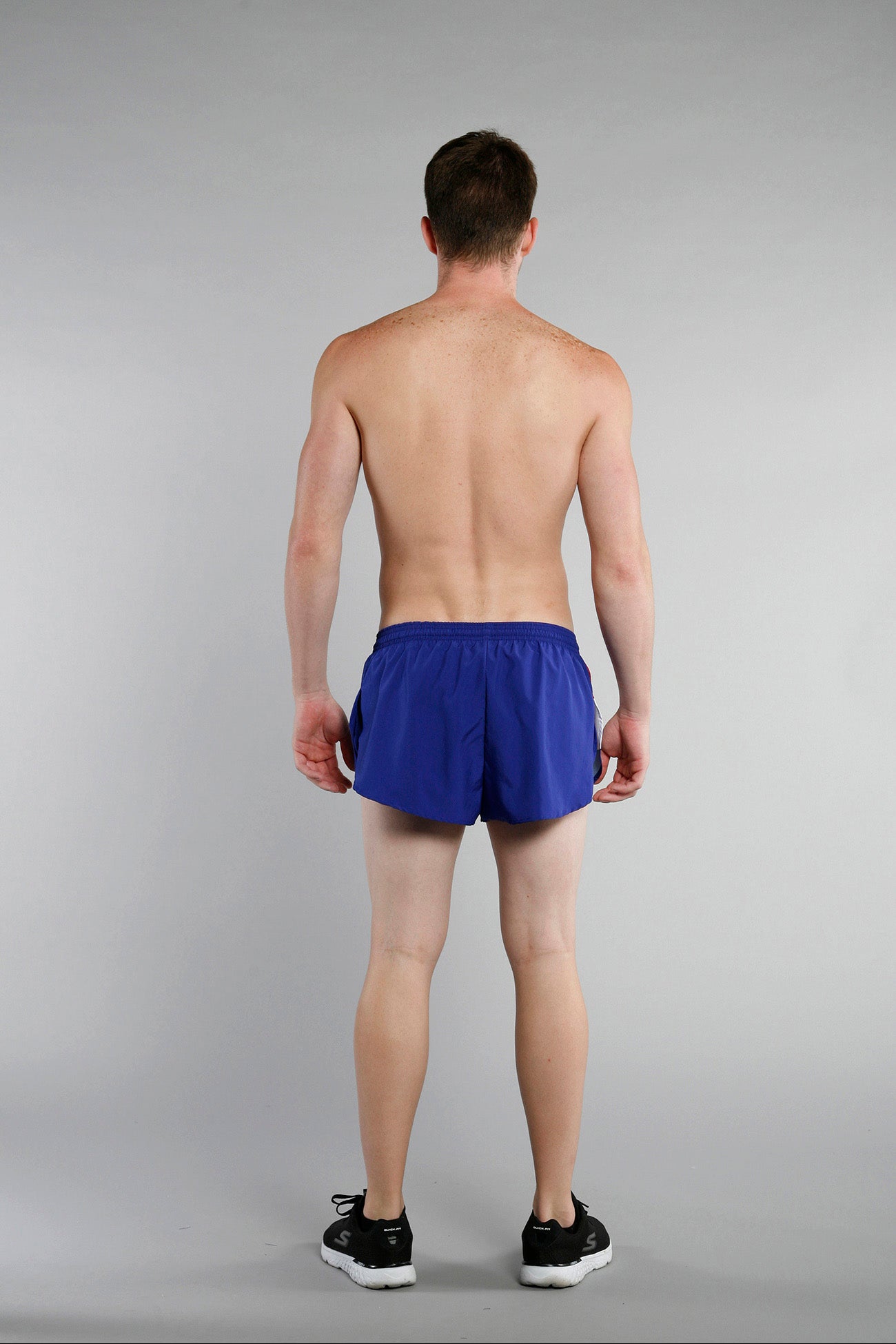 Men's Flag 1" Elite Split Shorts in royal blue, shown from the back on a male model wearing black Skechers sneakers, featuring a minimalist design with a split hem and elastic waistband representing Croatia's colors.