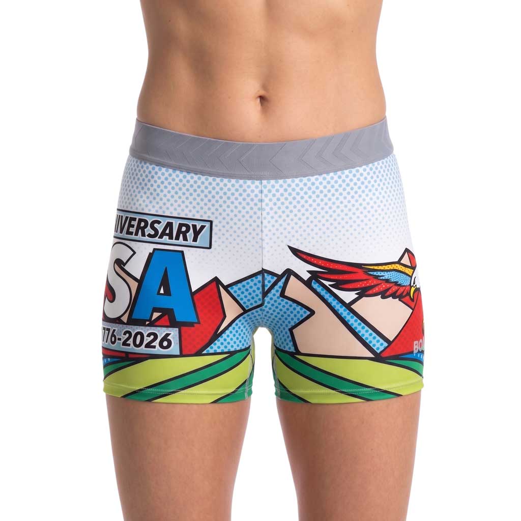 Women's Fly Fit Short - America 250 featuring a bold comic-style graphic print with a bald eagle, mountains, red, white, and blue colors, and "USA 1776-2026" anniversary text on a white halftone background with a gray waistband.